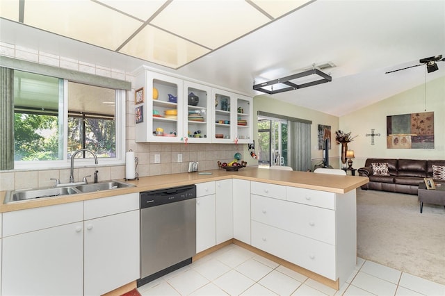 kitchen featuring a peninsula, a sink, dishwasher, light colored carpet, and open floor plan