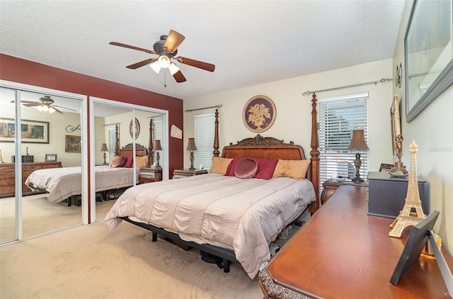 bedroom featuring multiple closets, carpet, a ceiling fan, and a textured ceiling