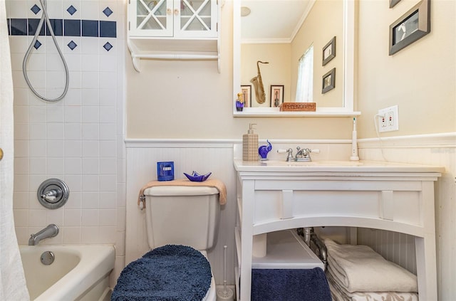 bathroom featuring a wainscoted wall, toilet, shower / bath combo, ornamental molding, and vanity