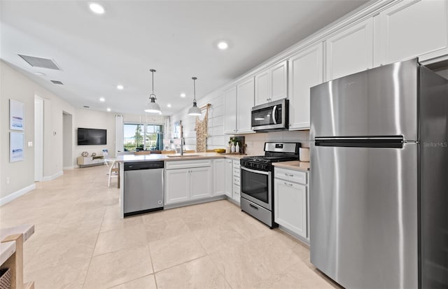 kitchen featuring visible vents, open floor plan, appliances with stainless steel finishes, a peninsula, and a sink