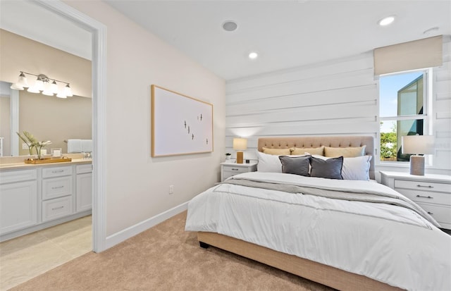 bedroom with recessed lighting, baseboards, ensuite bathroom, and light carpet