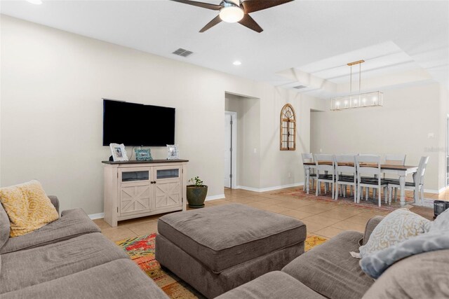 living room featuring light tile patterned floors, visible vents, ceiling fan with notable chandelier, and baseboards