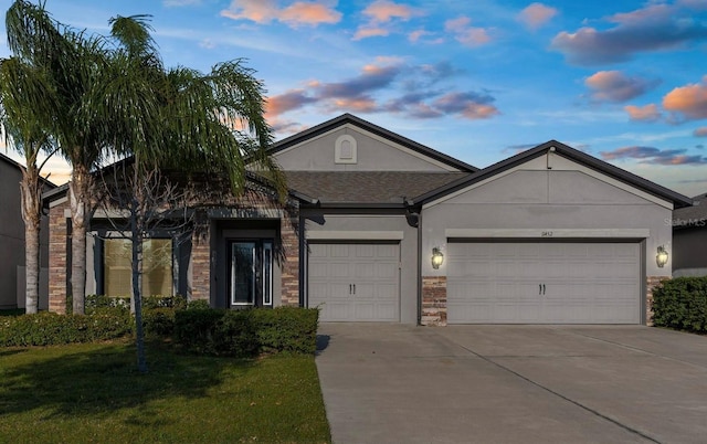 single story home with stucco siding, a yard, a garage, stone siding, and driveway