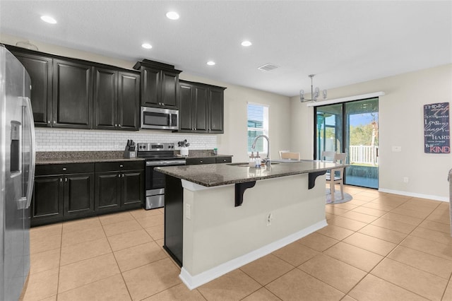 kitchen with a sink, dark cabinetry, light tile patterned floors, and stainless steel appliances