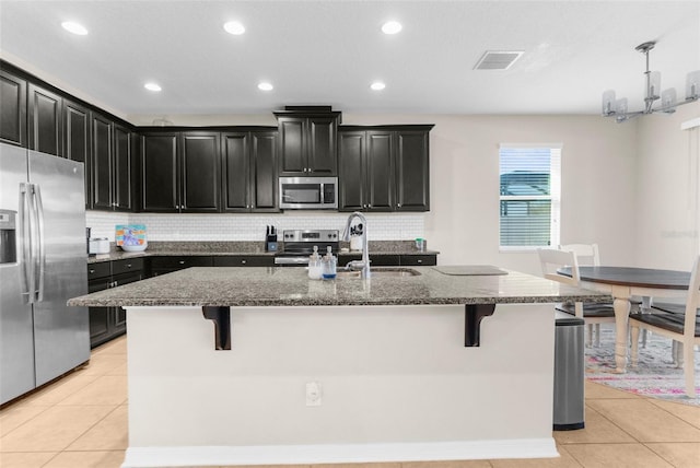 kitchen with light tile patterned floors, appliances with stainless steel finishes, and dark cabinets