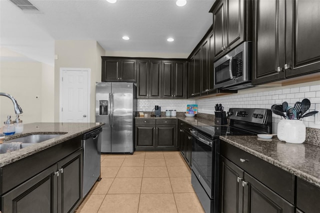 kitchen with visible vents, light tile patterned flooring, a sink, stainless steel appliances, and dark cabinets