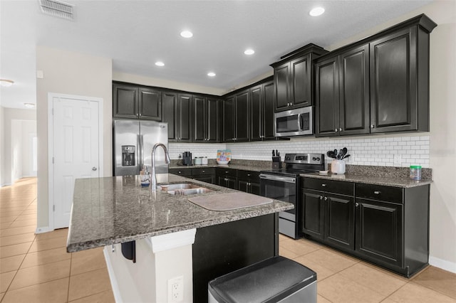 kitchen featuring visible vents, a sink, appliances with stainless steel finishes, light tile patterned flooring, and dark cabinets