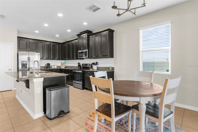 kitchen featuring visible vents, a sink, tasteful backsplash, appliances with stainless steel finishes, and light tile patterned flooring