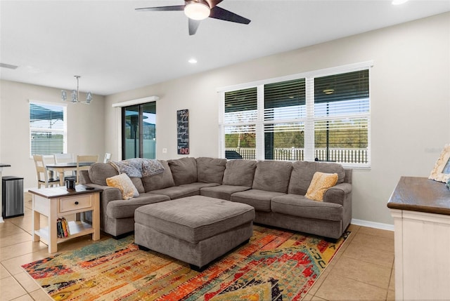 living area featuring light tile patterned floors, baseboards, recessed lighting, and ceiling fan with notable chandelier