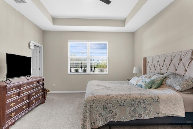 bedroom with a tray ceiling, baseboards, and light colored carpet