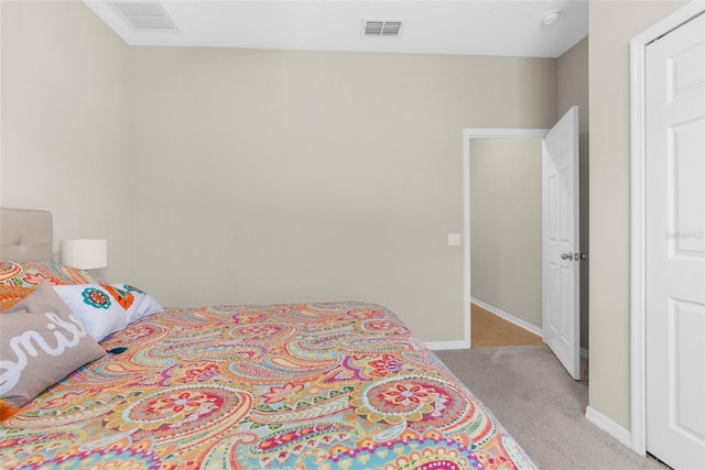 bedroom featuring baseboards, visible vents, and light carpet