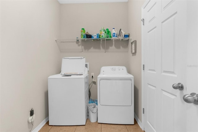 washroom with laundry area, light tile patterned flooring, baseboards, and washing machine and clothes dryer