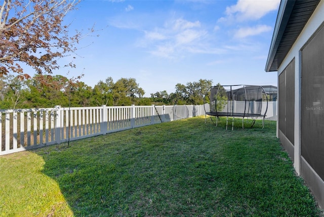 view of yard featuring a trampoline and a fenced backyard