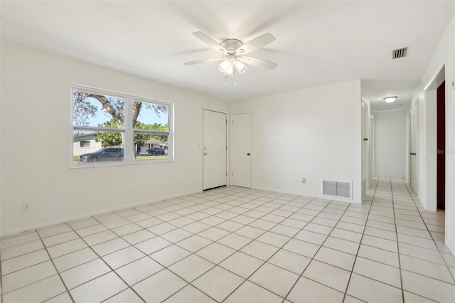 empty room with light tile patterned floors, baseboards, visible vents, and ceiling fan