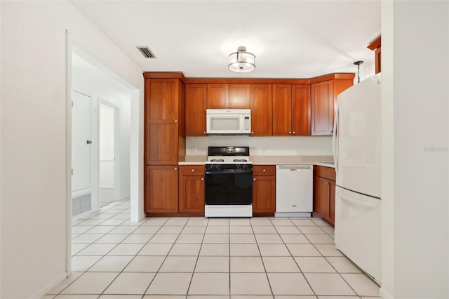 kitchen with white appliances, brown cabinetry, light countertops, and visible vents