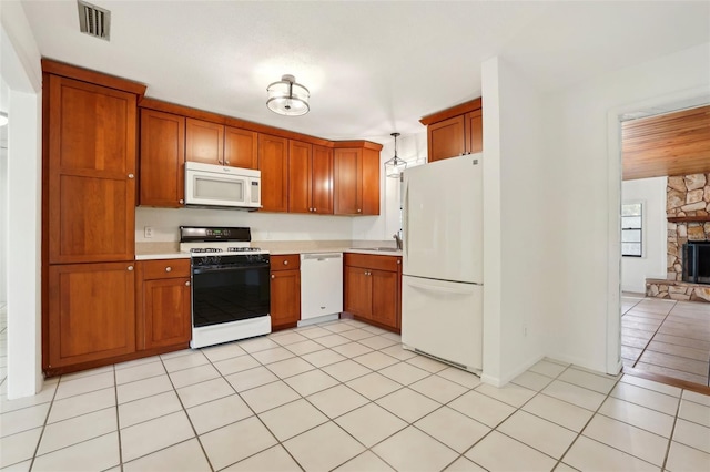 kitchen with white appliances, light tile patterned floors, a sink, light countertops, and brown cabinets