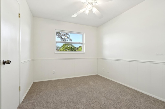 spare room featuring carpet flooring, a wainscoted wall, and ceiling fan