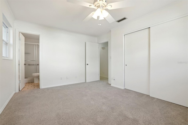 unfurnished bedroom with visible vents, connected bathroom, crown molding, light carpet, and a closet