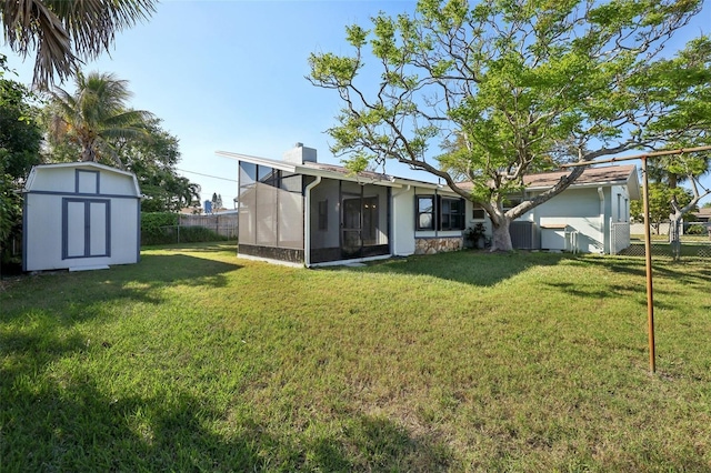 view of yard with an outbuilding, a storage shed, a sunroom, and fence