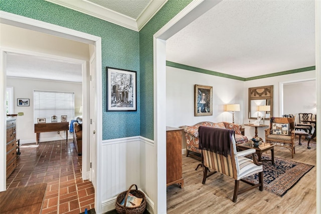 interior space with wallpapered walls, crown molding, a wainscoted wall, brick floor, and a textured ceiling