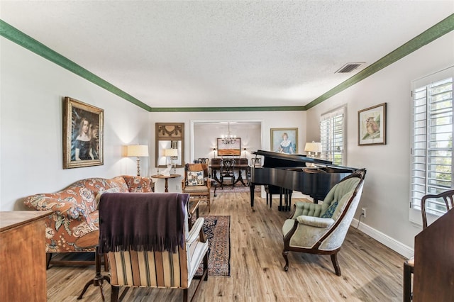 living room featuring wood finished floors, baseboards, visible vents, a textured ceiling, and crown molding