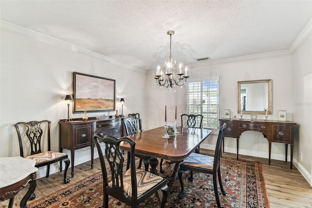 dining area featuring visible vents, a textured ceiling, crown molding, and wood finished floors