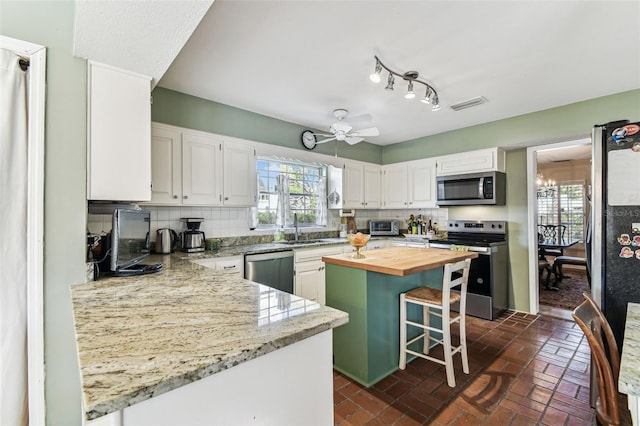 kitchen featuring tasteful backsplash, butcher block countertops, appliances with stainless steel finishes, and visible vents