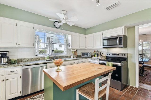 kitchen featuring visible vents, butcher block counters, stainless steel appliances, and decorative backsplash