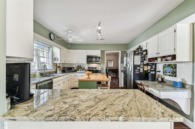 kitchen with backsplash, appliances with stainless steel finishes, white cabinets, and a sink