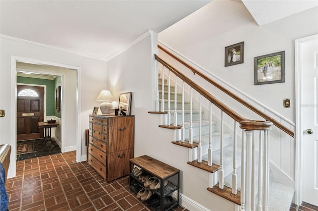 stairway featuring brick floor, baseboards, and crown molding