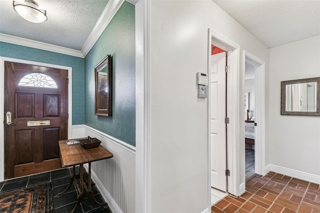 foyer with crown molding, brick floor, a wainscoted wall, and a textured ceiling