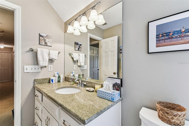 bathroom featuring a textured ceiling, toilet, vanity, and vaulted ceiling