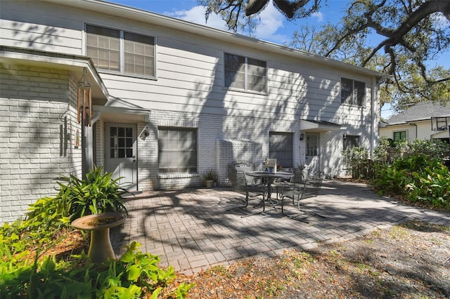 rear view of house with brick siding and a patio