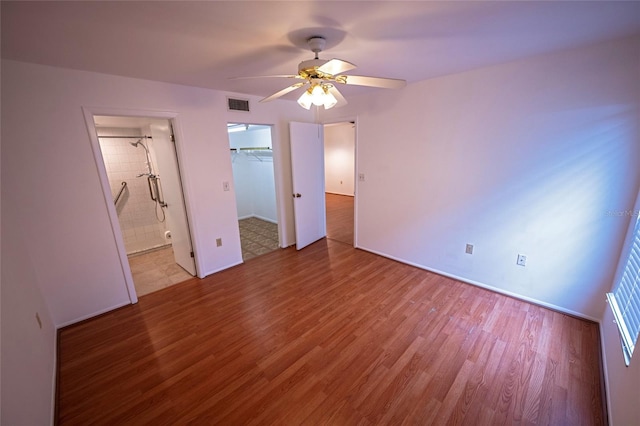 6125 113th St Unit 505, Seminole, FL 33772 - unfurnished bedroom with wood finished floors, ceiling fan, a walk in closet, and ensuite bath