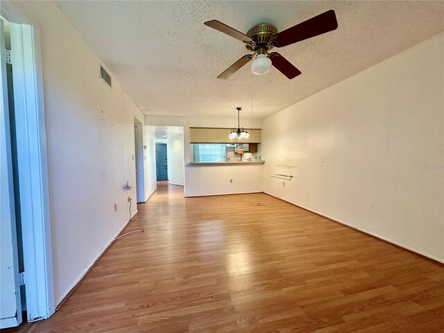 6125 113th St Unit 505, Seminole, FL 33772 - unfurnished living room with wood finished floors, a ceiling fan, a chandelier, and a textured ceiling
