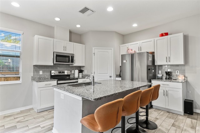 2612 E 26th Ave, Tampa, FL 33605 - kitchen with visible vents, a sink, light stone counters, appliances with stainless steel finishes, and white cabinets