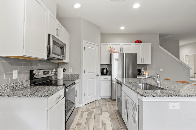 2612 E 26th Ave, Tampa, FL 33605 - kitchen featuring light stone countertops, a center island with sink, a sink, stainless steel appliances, and white cabinets