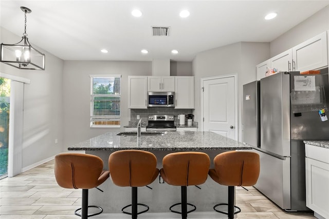 2612 E 26th Ave, Tampa, FL 33605 - kitchen with dark stone countertops, a breakfast bar area, visible vents, decorative backsplash, and appliances with stainless steel finishes