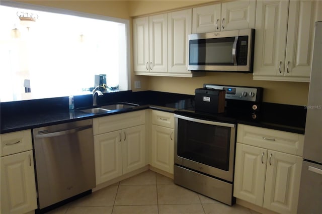 kitchen with a sink, stainless steel appliances, dark countertops, and white cabinets