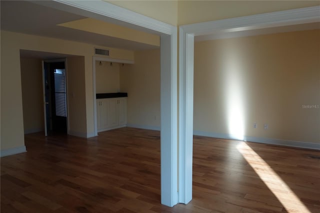 spare room featuring visible vents, baseboards, and wood finished floors