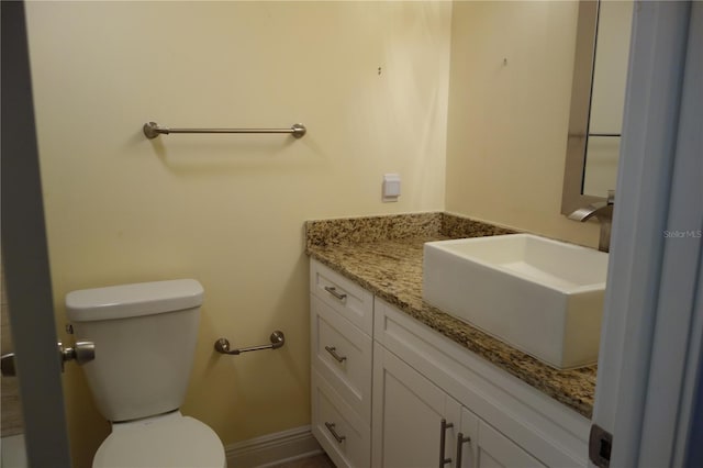 bathroom featuring toilet, vanity, and baseboards