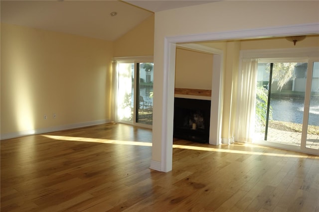 unfurnished living room with hardwood / wood-style flooring, a fireplace, baseboards, and vaulted ceiling