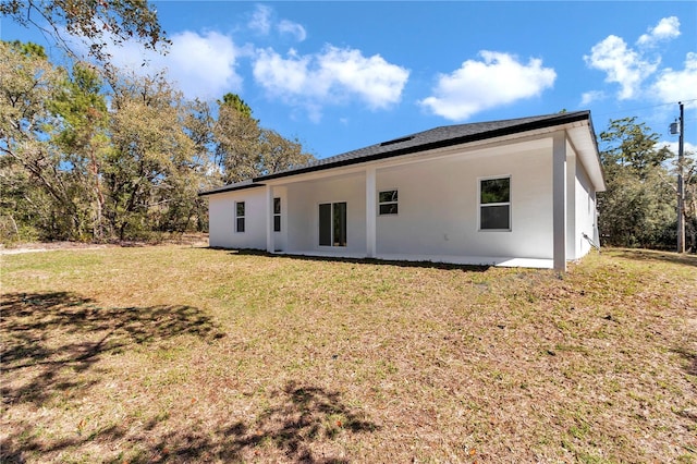 rear view of house with a lawn and stucco siding