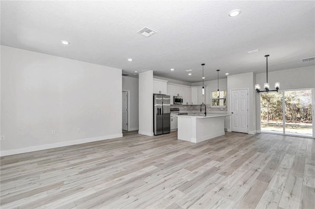 kitchen featuring visible vents, open floor plan, light countertops, appliances with stainless steel finishes, and an inviting chandelier