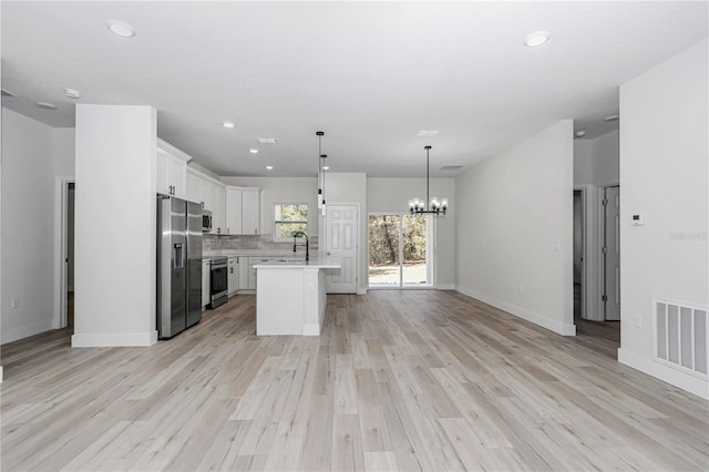 kitchen with visible vents, open floor plan, stainless steel appliances, an inviting chandelier, and light countertops