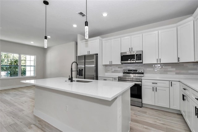 kitchen with visible vents, light wood finished floors, a sink, appliances with stainless steel finishes, and backsplash