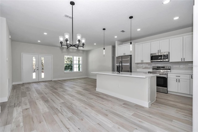 kitchen featuring stainless steel appliances, open floor plan, tasteful backsplash, and light wood-style flooring