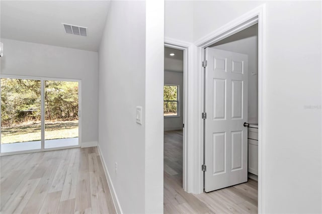 hallway featuring light wood finished floors, visible vents, and baseboards