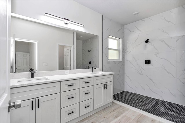 bathroom with double vanity, wood finished floors, a marble finish shower, and a sink