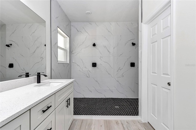 full bathroom with wood finished floors, vanity, and a tile shower